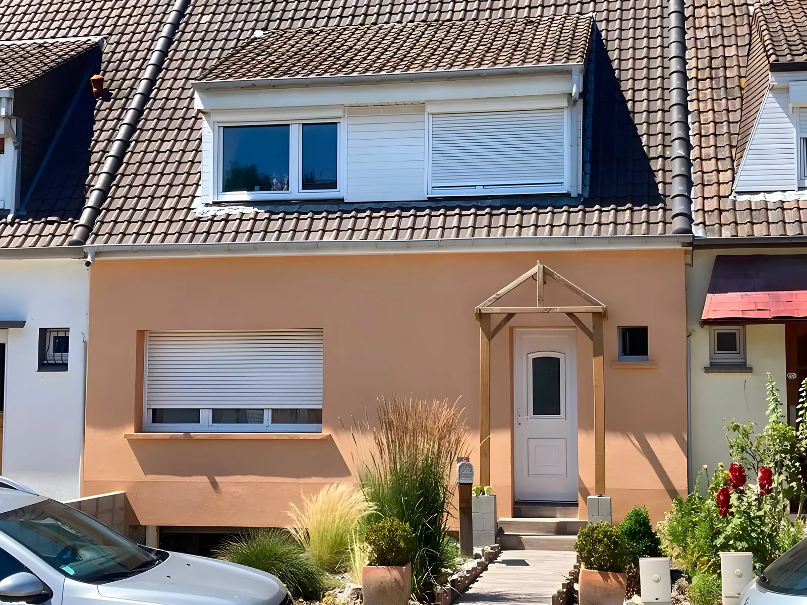 Maison individuelle à façade orange avec volets roulants blancs et porte d'entrée à Isques