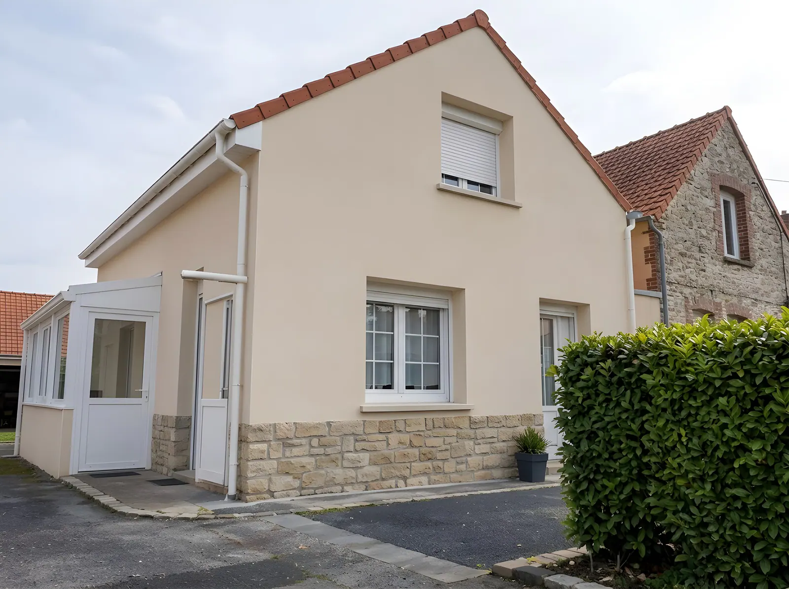 Maison rénovée avec façade enduite beige et soubassement en pierre à Isques