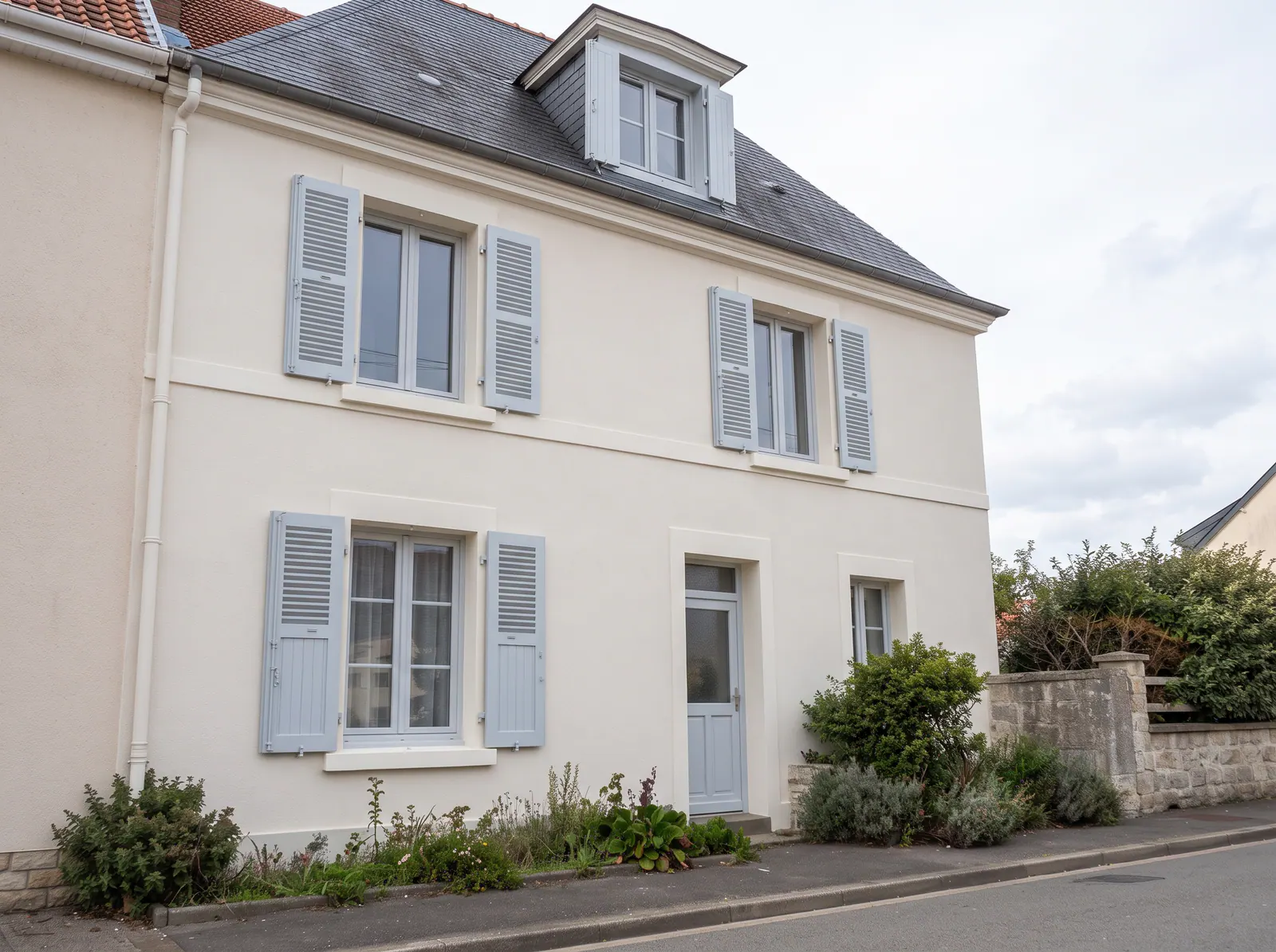 Maison de village rénovée à Isques avec façade claire et volets gris, isolation thermique et ravalement