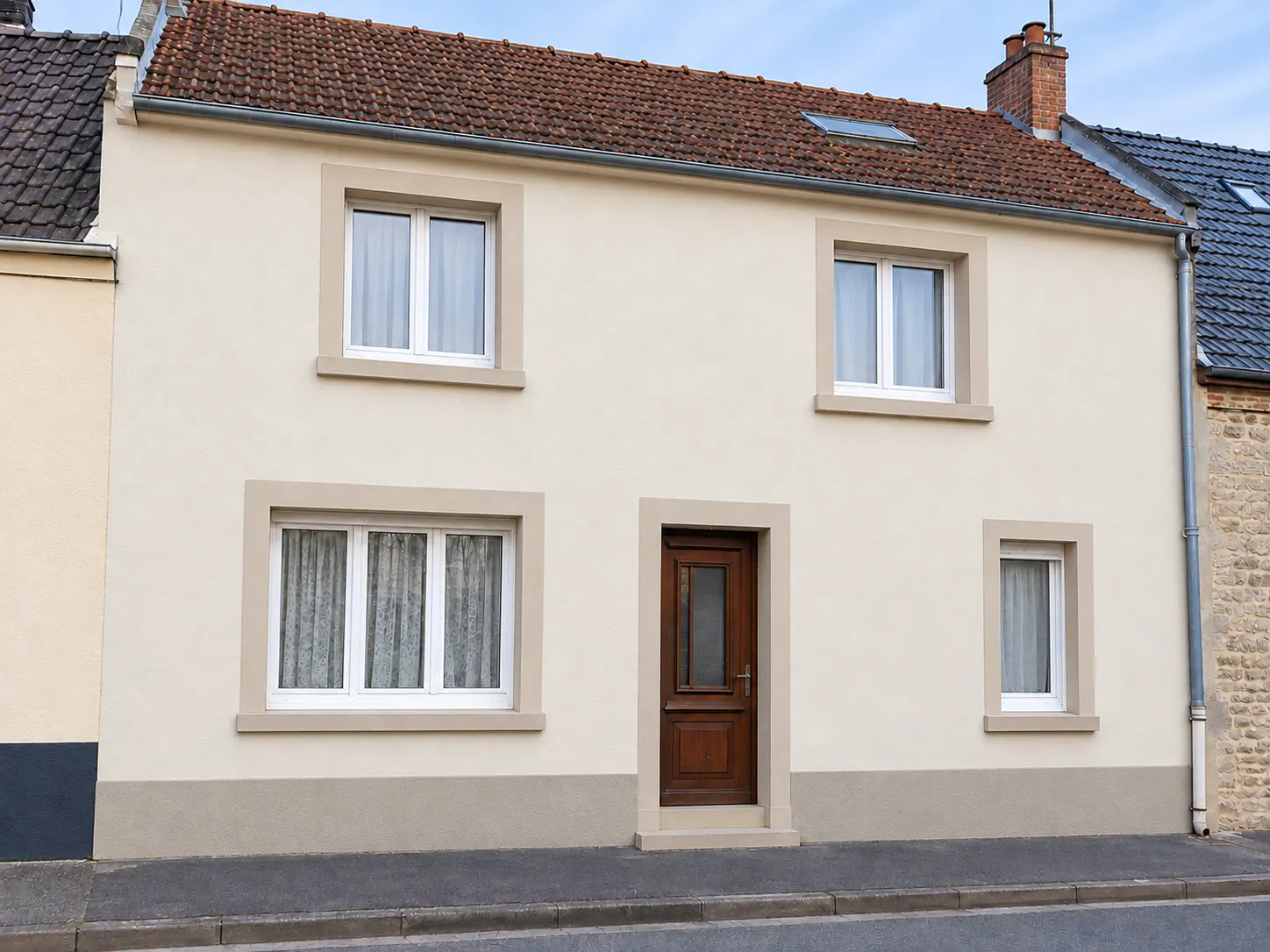 Façade rénovée d'une maison à Isques avec enduit beige et pierre, fenêtres blanches et porte bois
